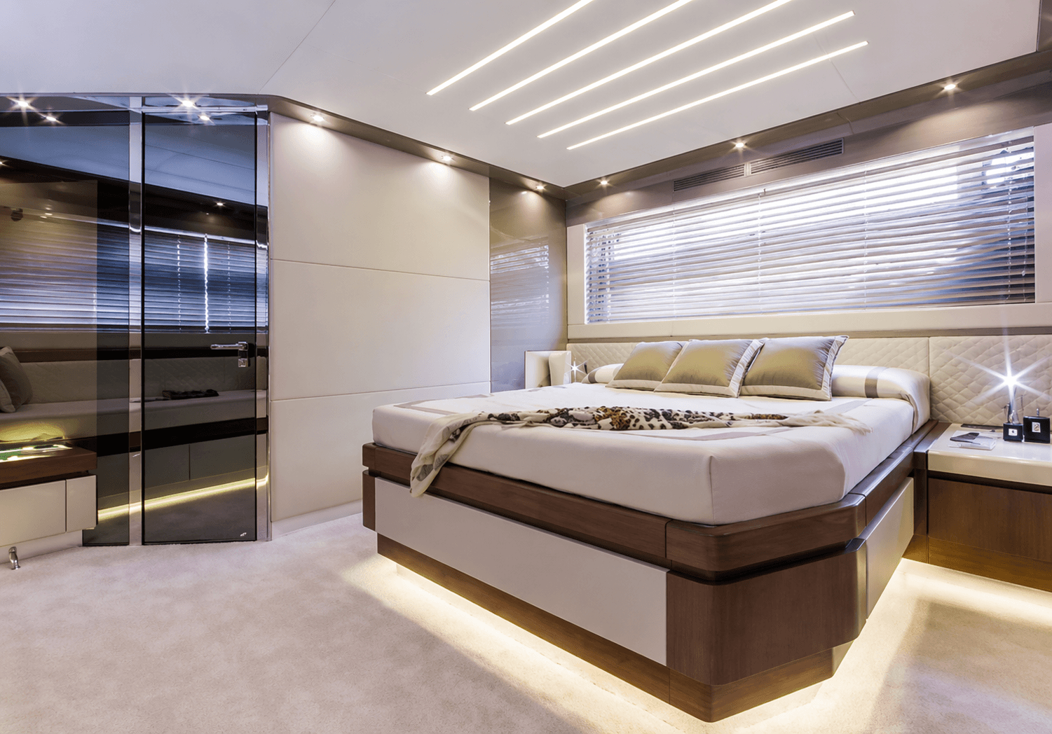 Camera da letto di yacht luxury con rivestimento pareti su misura, letto matrimoniale con illuminazione LED integrata e finiture in legno e pannelli imbottiti